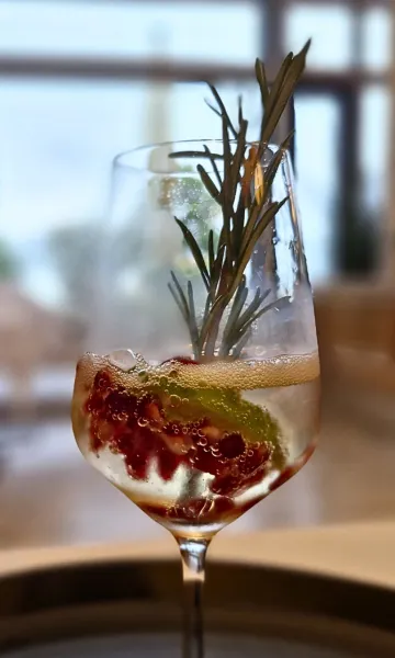 Ein Cocktail mit Beeren und Kräutern dekoriert auf einem Tablett für Getränke und Bar Catering